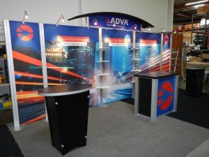 RENTAL: RE-2009 Arch Canopy, Halogen Arm Lights, RE-1202 Counter, (2) RE-1201 Counters, and Clear Acrylic Shelves. Tension Fabric Graphics, and Sintra Header and Counter Graphics