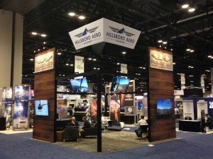 Custom Hybrid Island Exhibit with Tension Fabric Graphics, Monitors, Lounge, Aero Hanging Sign, Suspended Graphics, and Storage